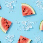 Summer creative wallpaper. Watermelon pattern with sunlight. Sliced fruit with ice on blue background